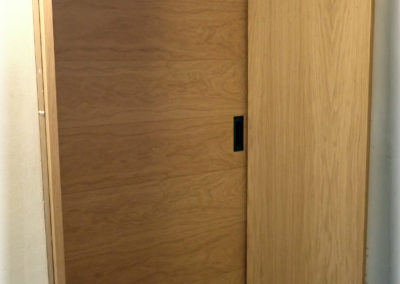 Porte coulissante plaquée chêne et grande embrasure adaptée au mur.