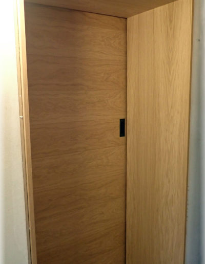 Porte coulissante plaquée chêne et grande embrasure adaptée au mur.